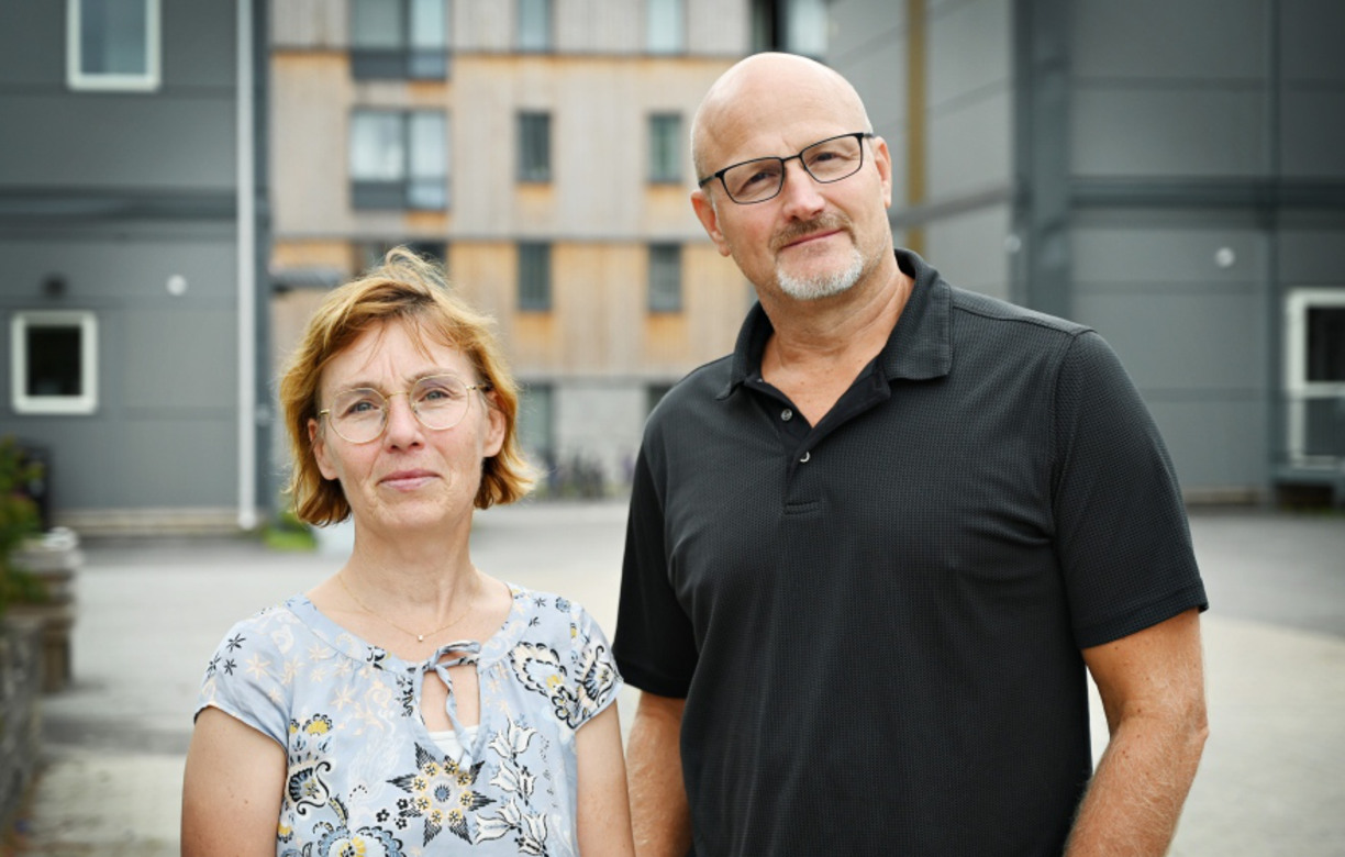 Johanna Sundbaum och Phillip Tretten står utomhus och kollar in i kameran och ler, i bakgrunden syns byggnader och grönska.