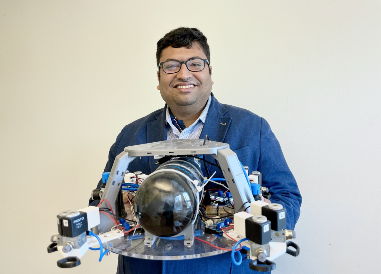 Avijit Banerje ler mot kameran med en liten robot i händerna